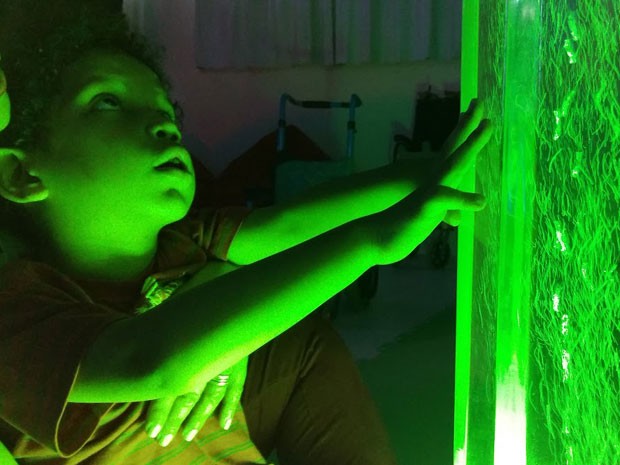 Criança toca torre borbulhante em sala com iluminação verde
