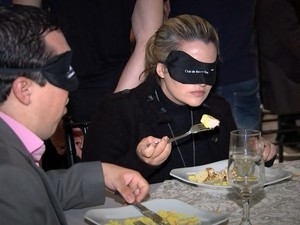 Pessoas jantam com os olhos vendados.