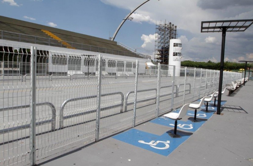 Foto do Sambódromo do Anhembi vazio à luz do dia com cadeiras reservadas às pessoas com deficiência.
