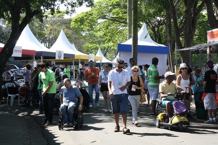 Foto de um espaço aberto, com tendas montades e pessoas de diversas idades circulando, entre elas, cadeirantes