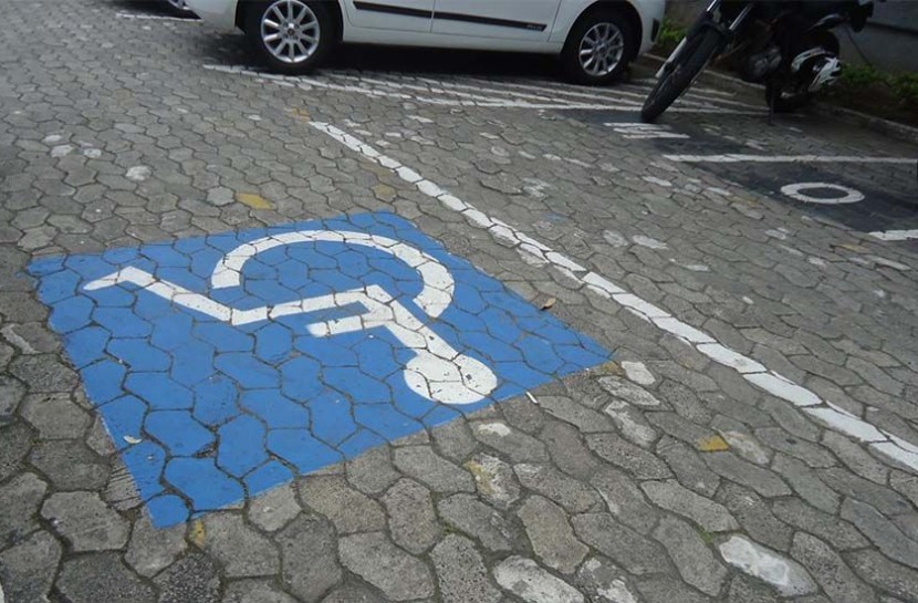 Foto de uma vaga de estacionamento exclusiva para pessoa com deficiência, com o símbolo de um cadeirante pintado em azul e branco