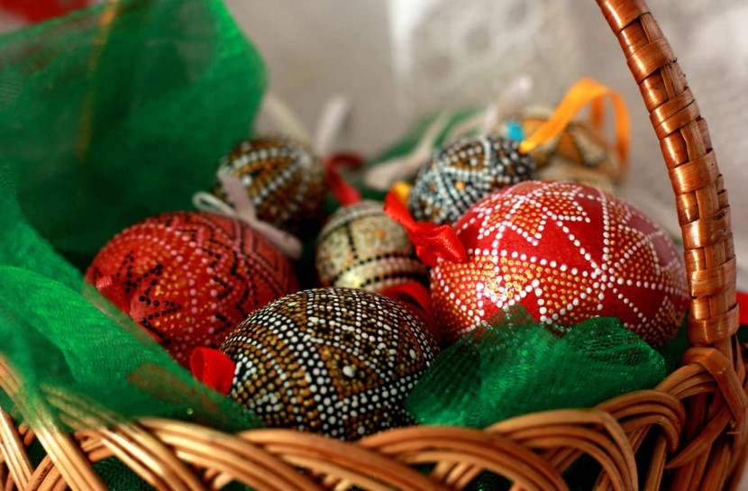 Foto em close de uma cesta com ovos de galinha pintados com adornos nas cores de vermelho e dourado
