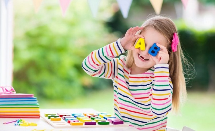 Foto de uma menina de oito anos segurando letras coloridas