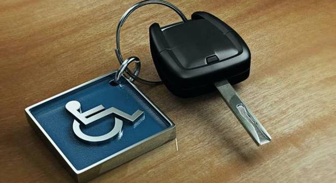 Foto de uma chave de carro presa a um chaveiro de metal quadrado; ele é azul e tem o símbolo de pessoa com deficiência física