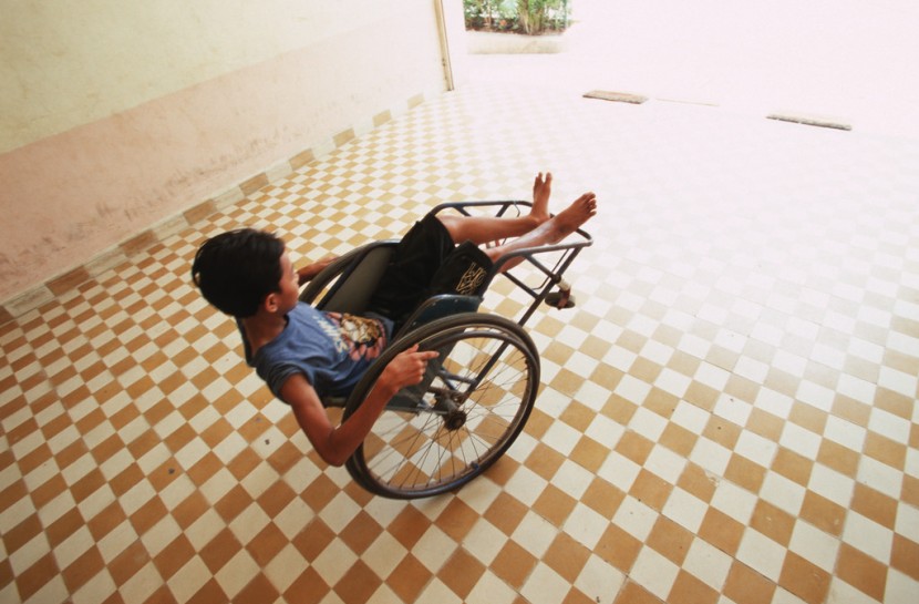 Jovem com deficiência brinca com sua cadeira de rodas em um pátio aberto e iluminado