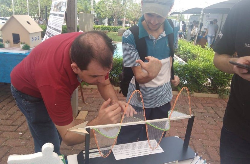Foto do professor Eder Pires de Camargo mostrando um projeto de física para um aluno