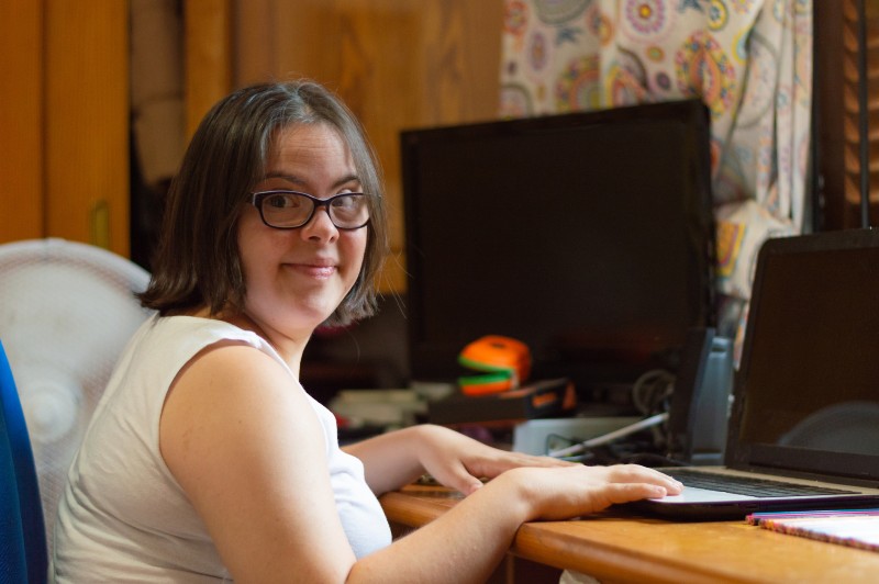 Foto de uma mulher jovem com síndrome de Down usando um laptop.